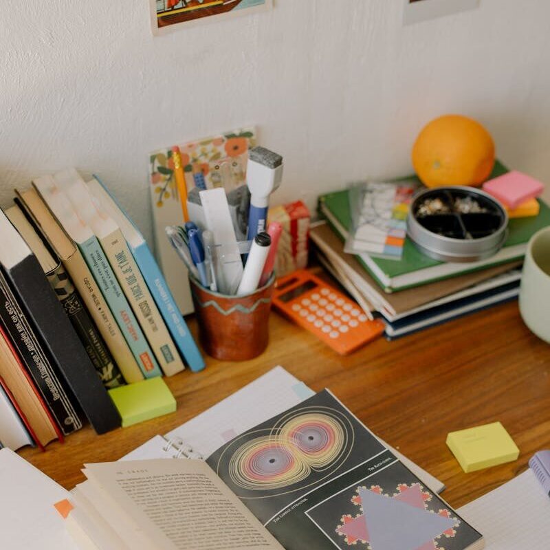 A study desk filled with open books, notebooks, and colorful stationery for academic work.